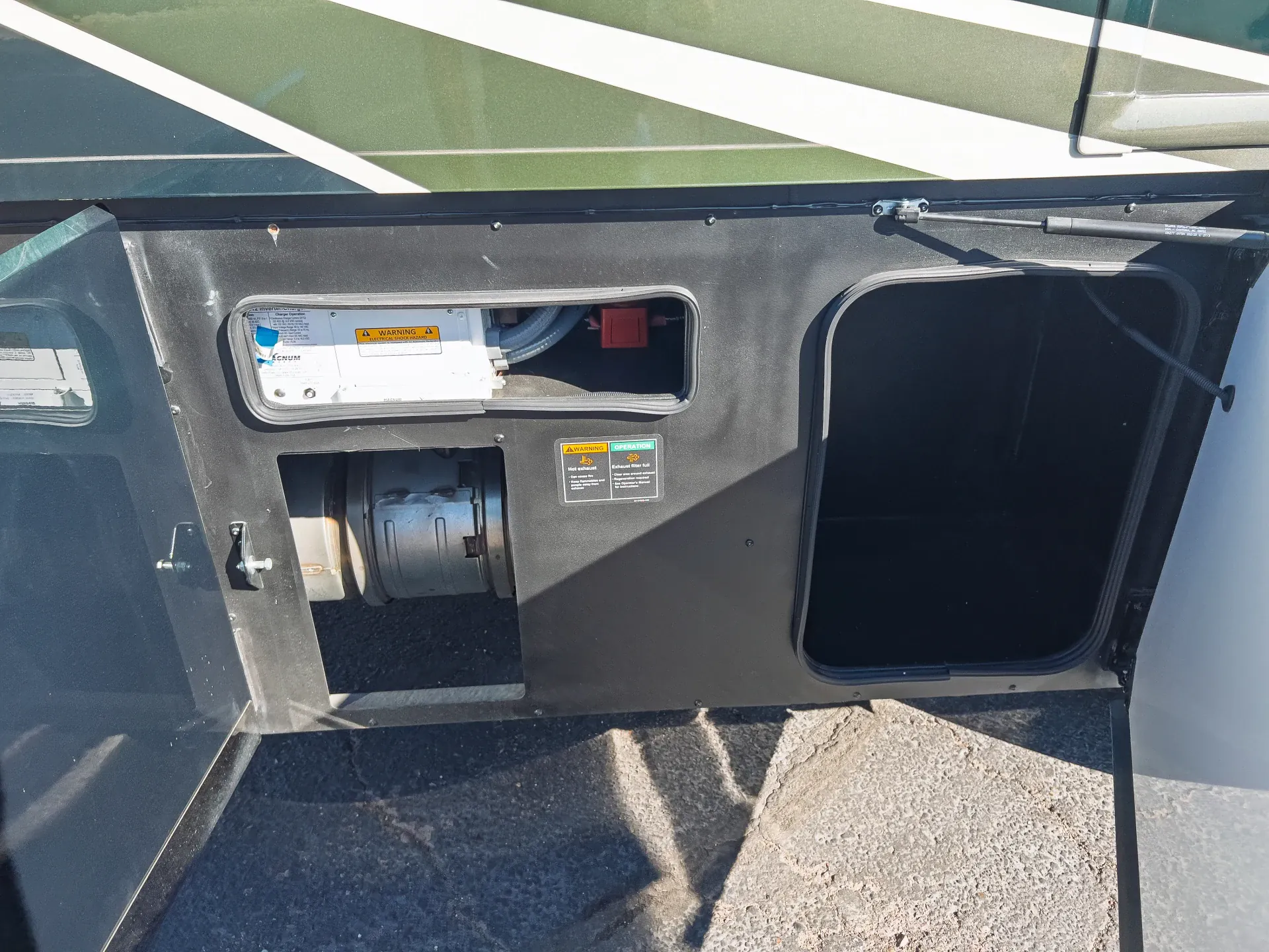2027 Fleetwood Discovery LXE 40M — Exterior access panel visibly shows installed equipment, warning labels, and a mechanical component