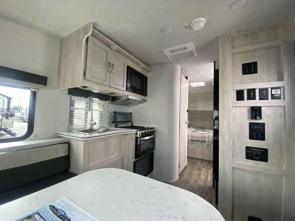 2026 Gulf Stream Vista Cruiser 19ERD — Travel trailer interior overview with kitchen appliances, dinette table, wall controls, and open doorway to the bed