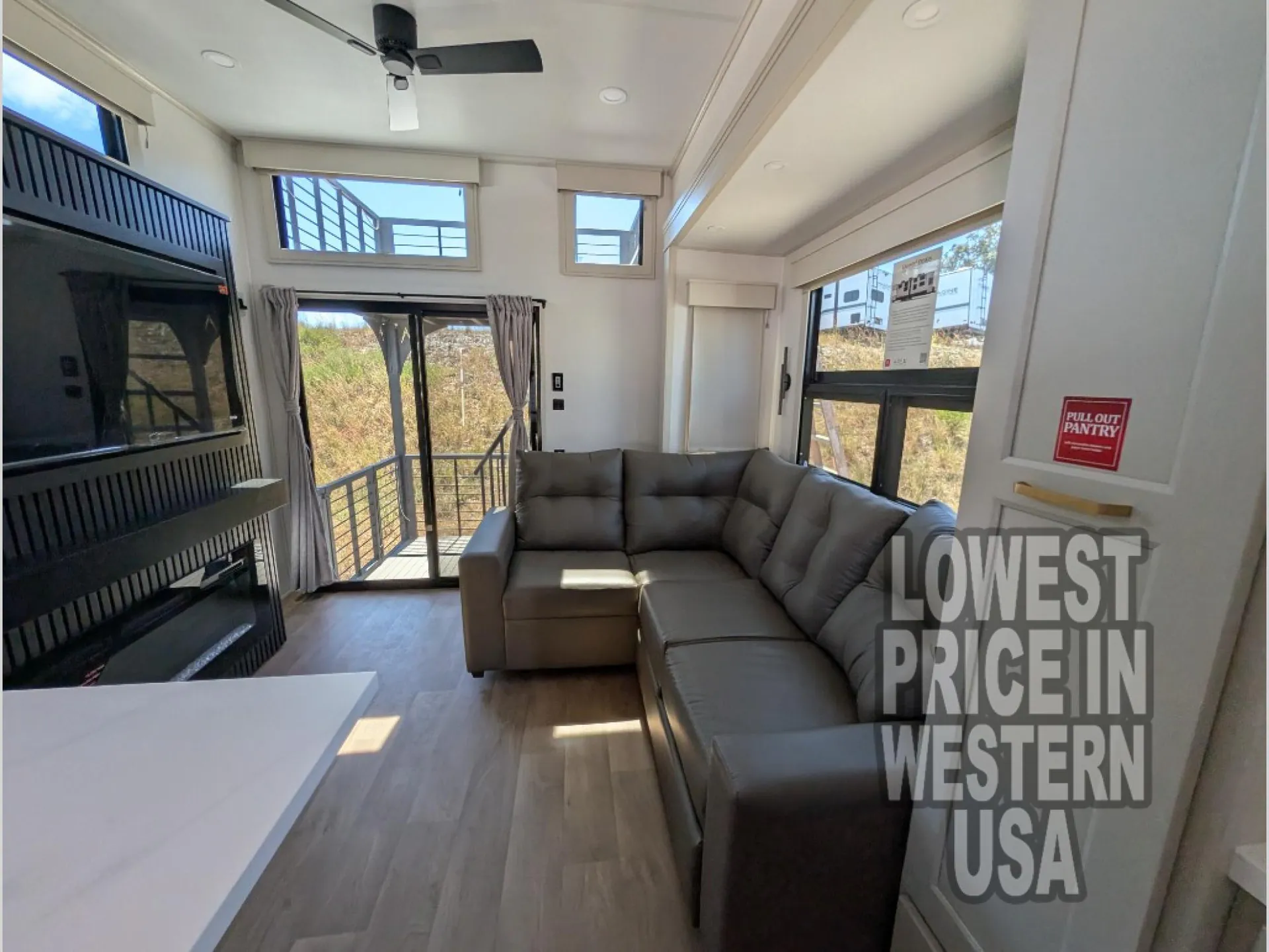 2026 Grand Design Foundation 42GD — Destination trailer living area with sectional sofa, fireplace, television, windows, and glass door to an exterior deck