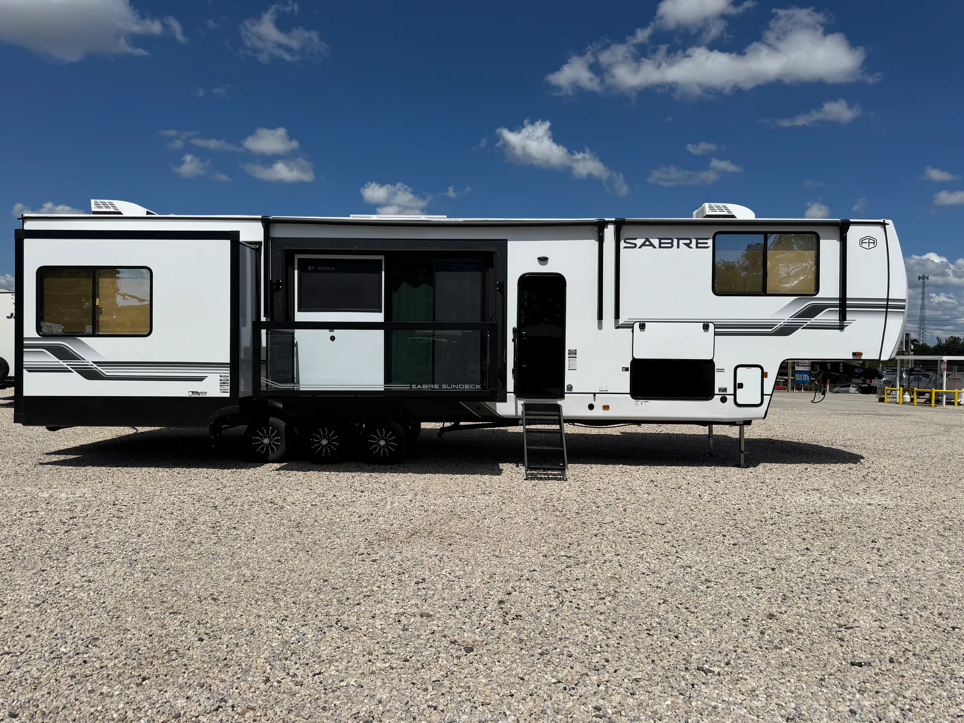 2027 Forest River Sabre 38RVHUNTER — Full side outdoor photograph visibly shows the RV shell, slide-outs, entrance, windows, wheels, and exterior compartments