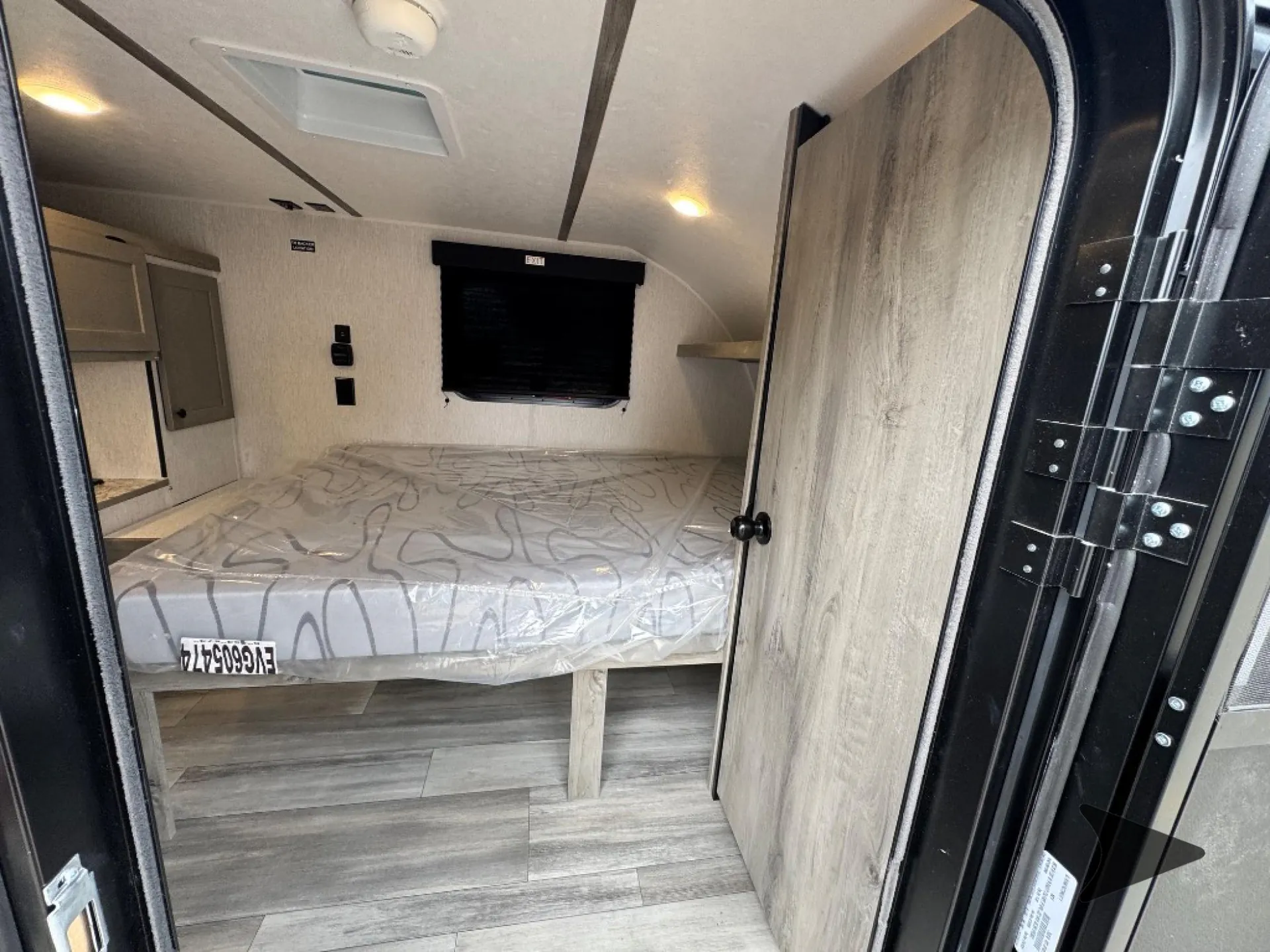 2026 Wayfinder GO LITE LTD Solo — Main enclosed bed with television and storage, viewed from the doorway toward the adjacent kitchen counter
