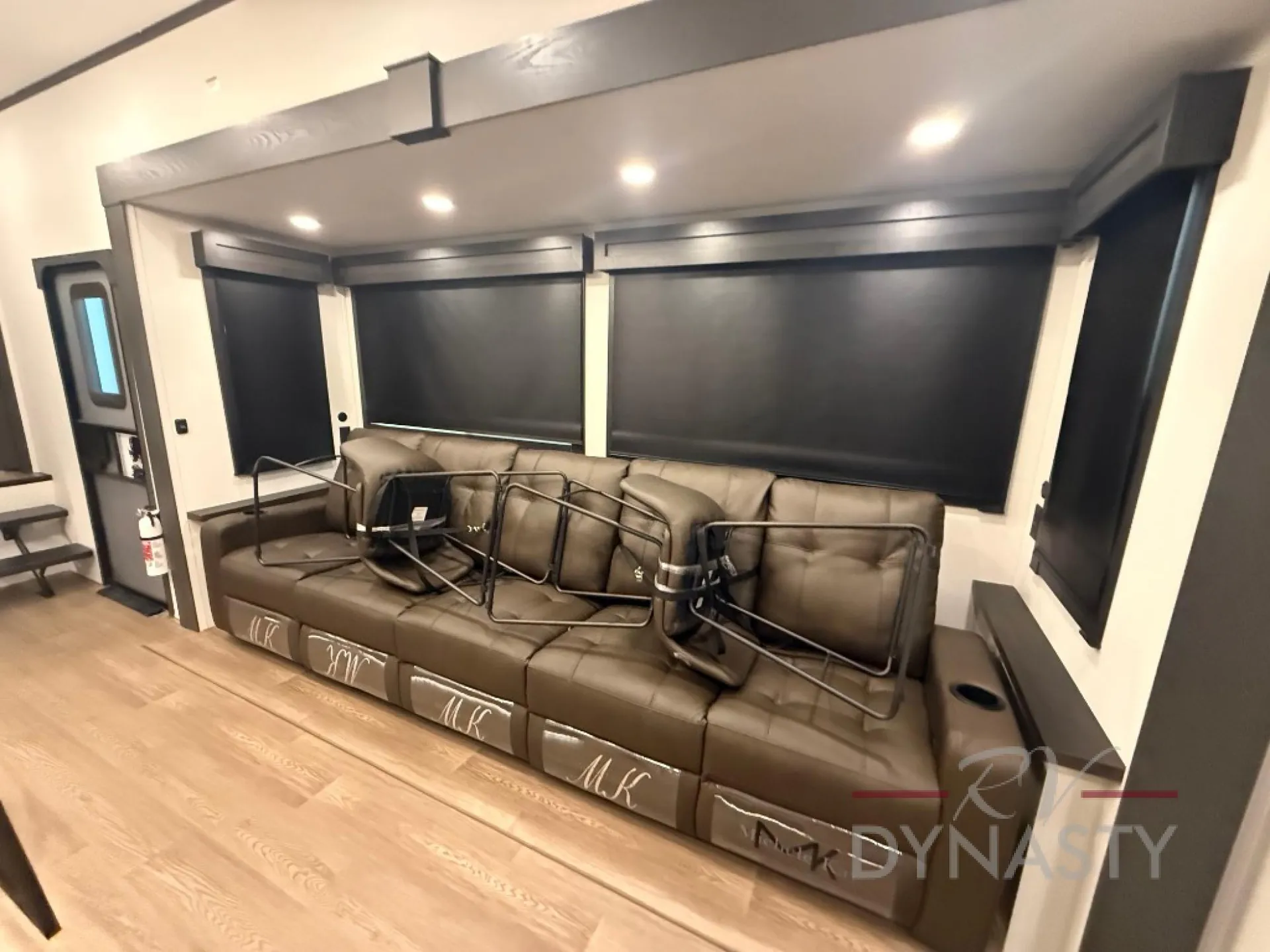 2027 Forest River Sanibel 40BUNK — Living room sofa beneath large windows with a wall-mounted television at right