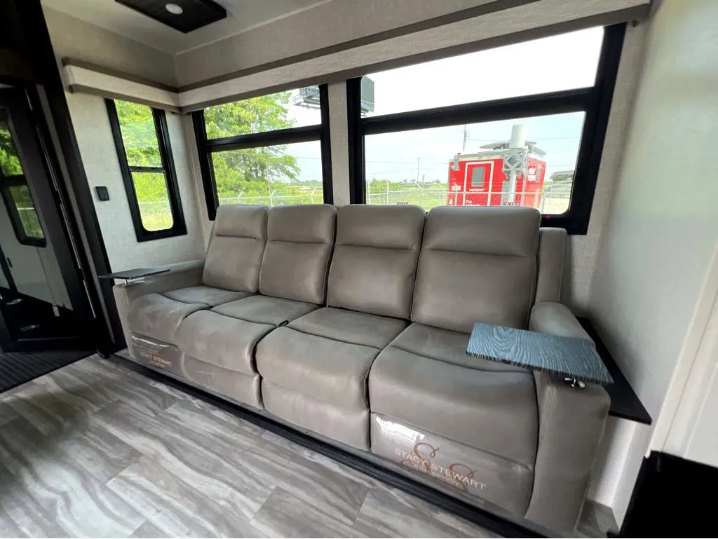 2025 Jayco Seismic Luxury Series 4113 — Four-seat recliner sofa beneath large windows in the fifth-wheel living area