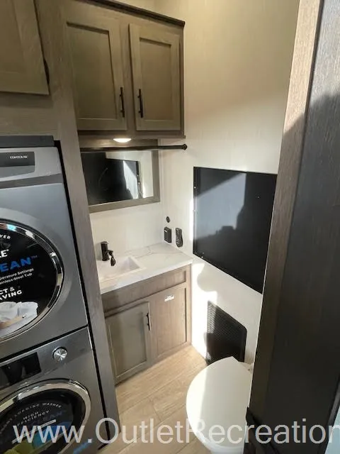 2026 Forest River Arctic Wolf 38LEAH.G — Bathroom vanity with sink, mirror, overhead cabinets, wall-mounted television, and toilet edge