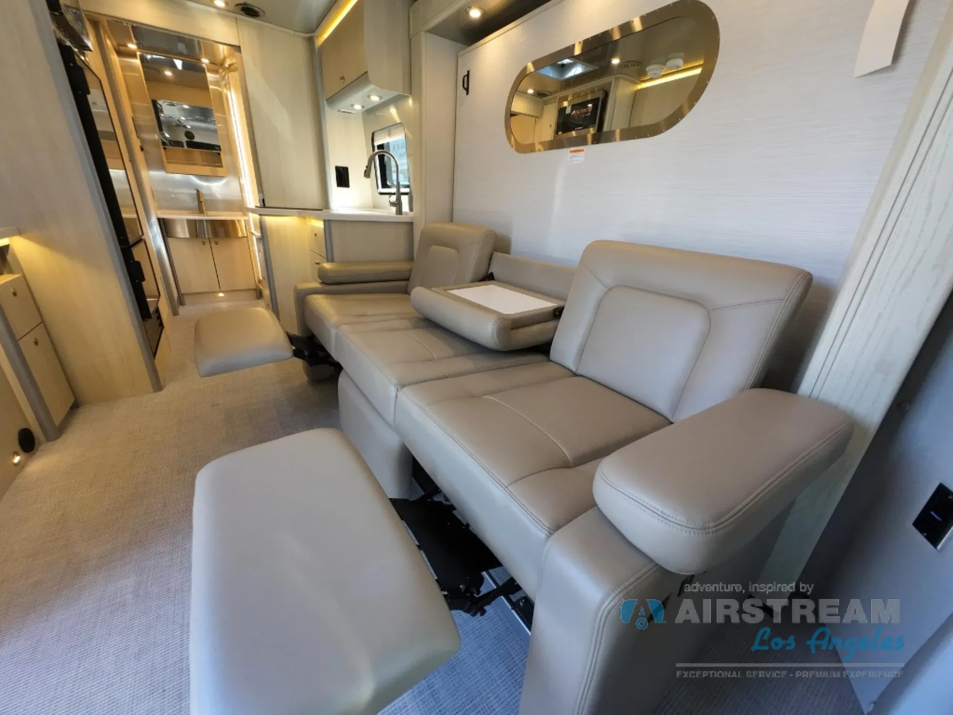 2026 Airstream Atlas Murphy Suite — Class B van lounge with facing recliners, fold-down table, and compact kitchen counter visible behind the seating