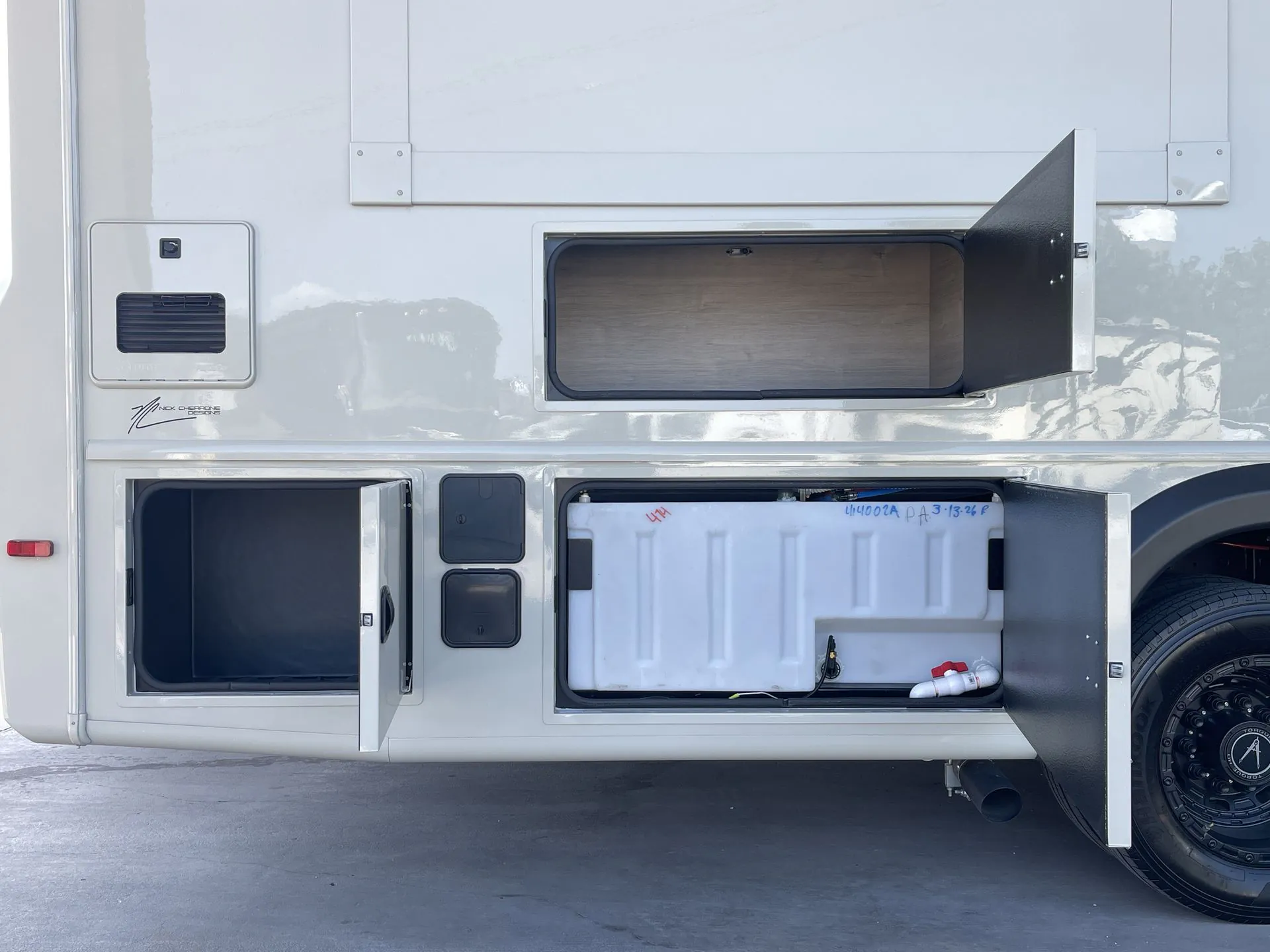 2027 Grand Design Lineage Series F 31ZW — Exterior service compartments visibly contain utility equipment, connections, and a tank-like component