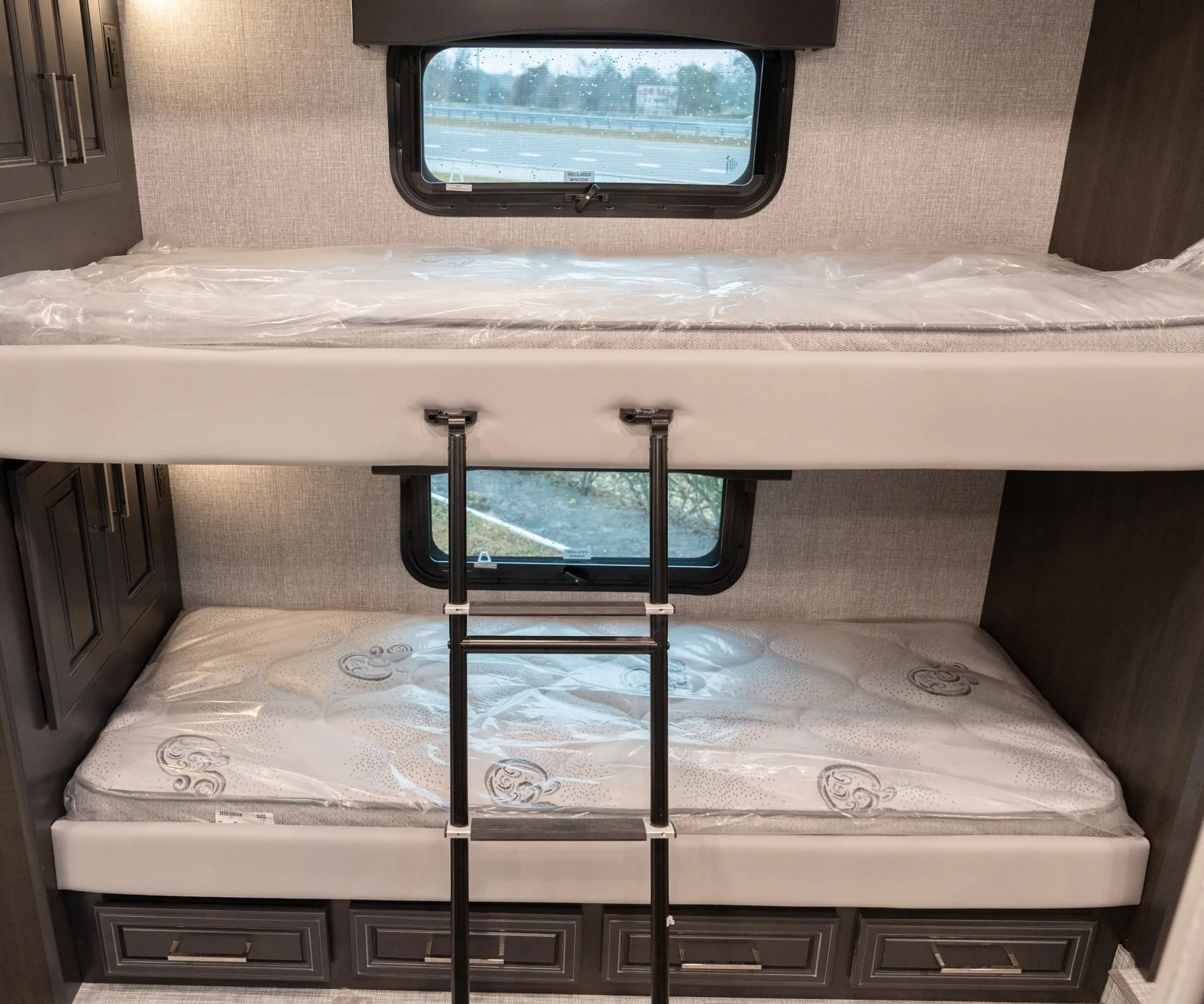 2026 Fleetwood Discovery LXE 40G — Over-cab bunk with ladder, mattresses, surrounding cabinets, and storage drawers below