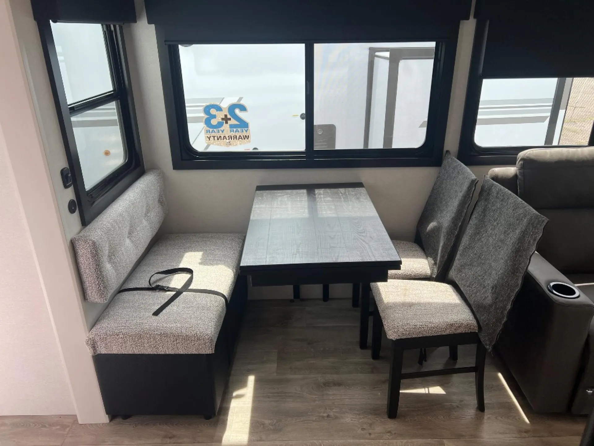 2027 Jayco Eagle 355MBQS — Fifth wheel dinette with booth seating and chairs beside a living-area recliner