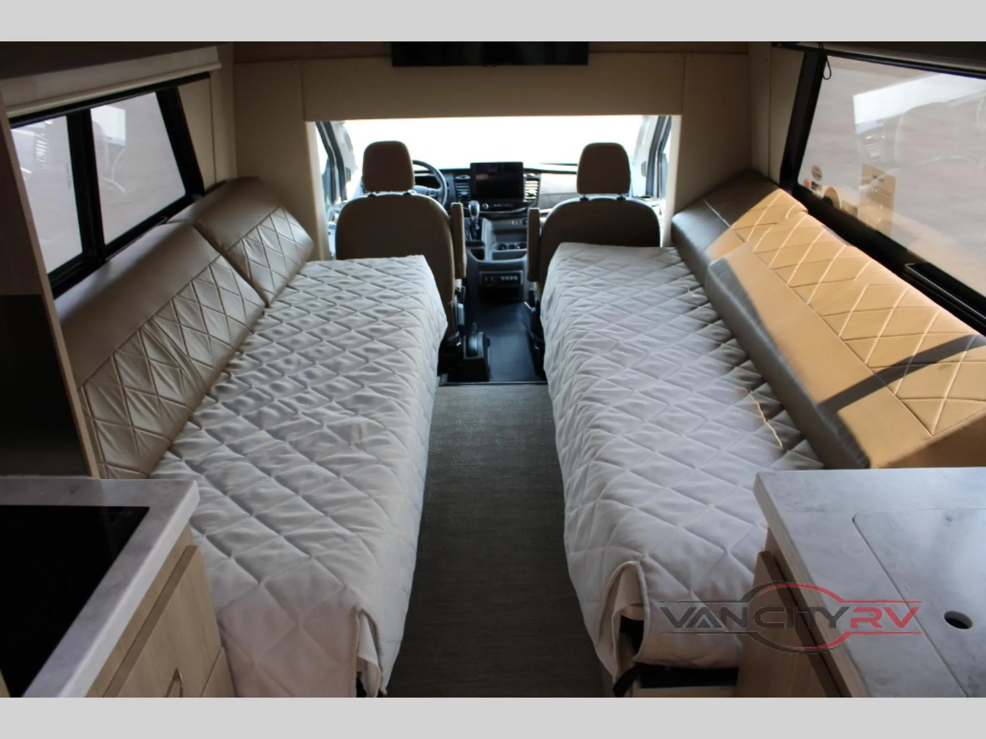 2025 Chinook RV Maverick SS — Two opposing upholstered sleeping surfaces lead toward the Class B van cockpit and dashboard