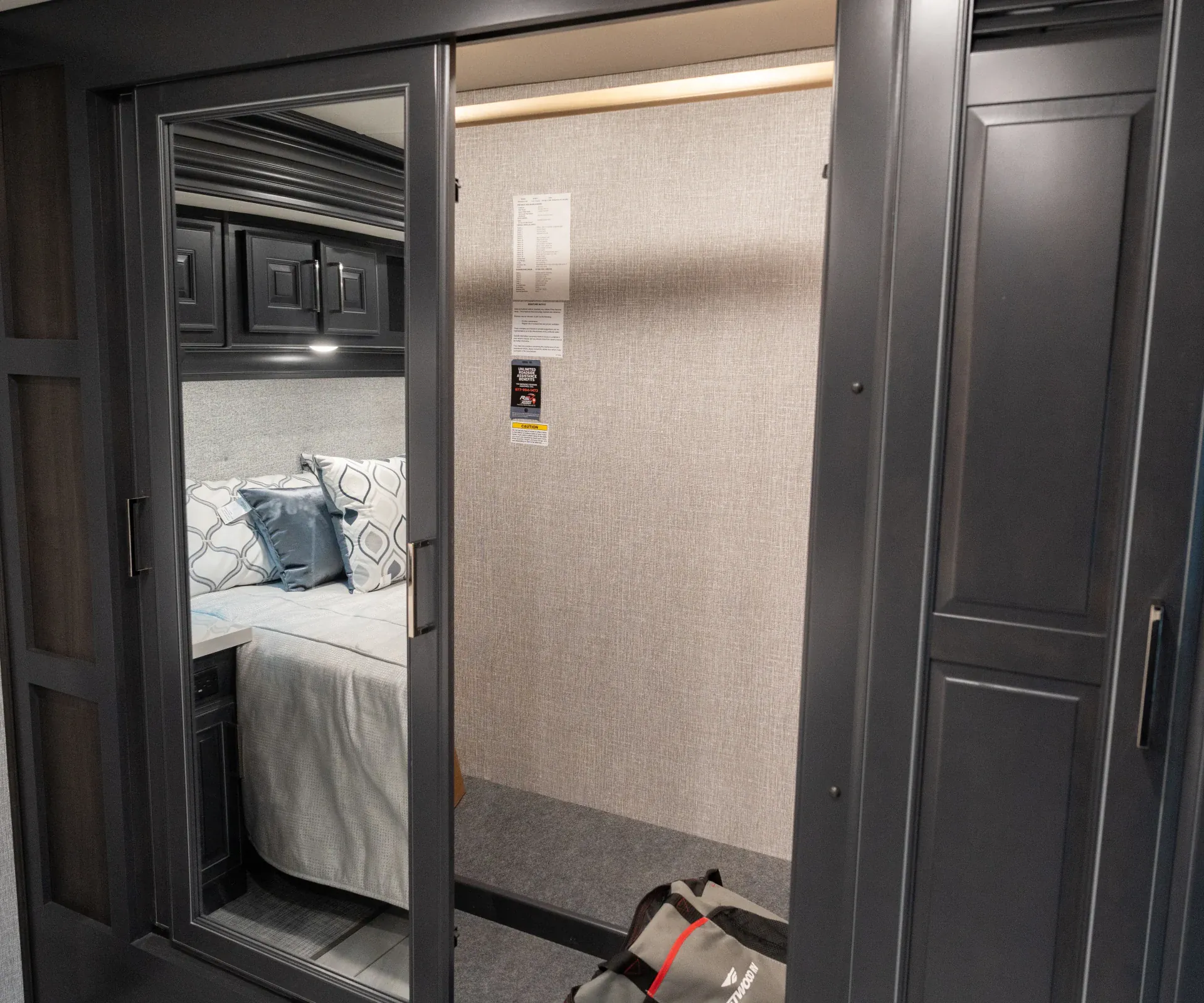 2026 Fleetwood Discovery LXE 40G — Bedroom wardrobe with mirrored doors, open hanging closet, and bed reflected at left