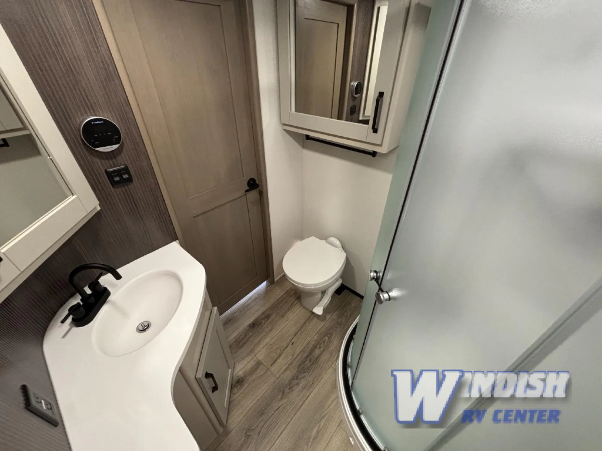 2027 Grand Design Reflection 362TBS — Bathroom with a toilet, corner shower, curved vanity sink, medicine cabinet, and closed interior door