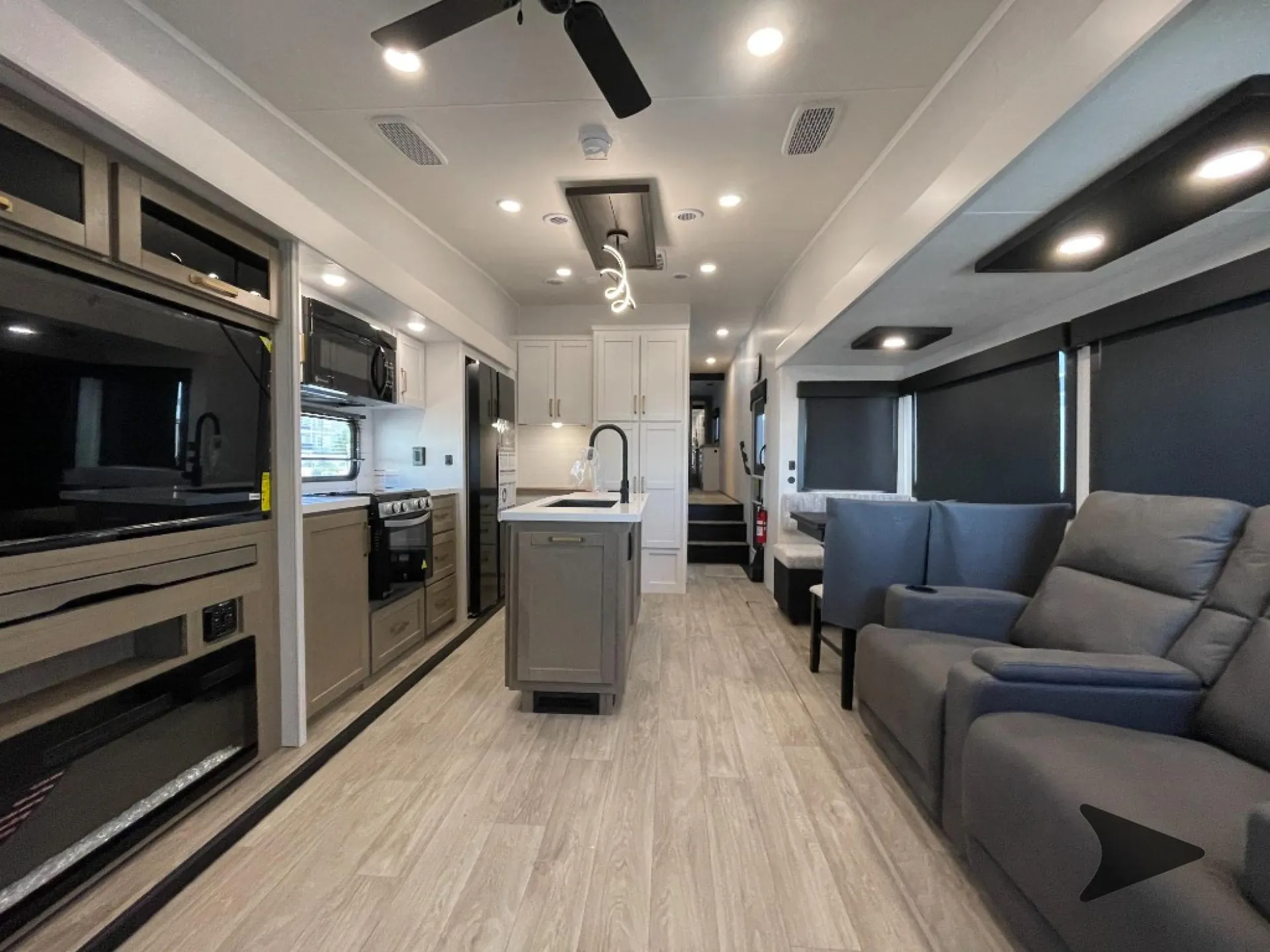 2027 Jayco Eagle 355MBQS — Fifth wheel interior overview connecting recliners and sofa seating with the kitchen island, appliances, and dinette