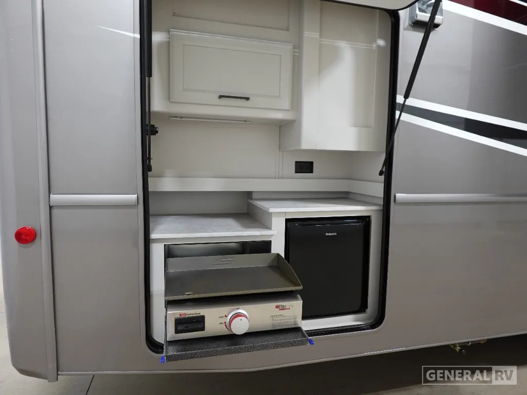 2026 Holiday Rambler Invicta 36Y — Exterior-mounted compartment visibly contains a slide-out cooktop and refrigerator