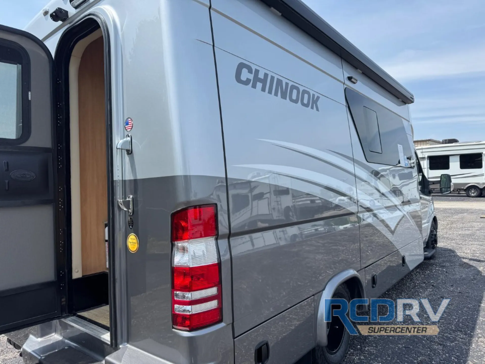 2025 Chinook RV Maverick SS — Exterior side/rear photograph visibly shows the RV body, open entry door, awning, graphics, and wheel