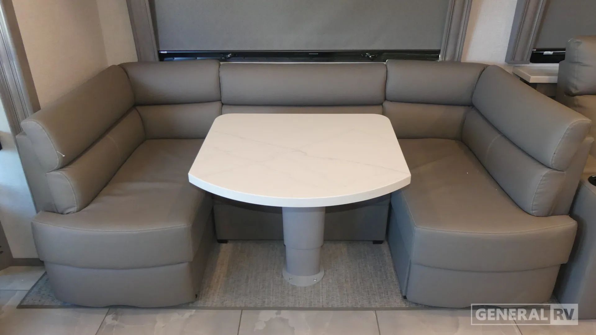 2026 Fleetwood Discovery LXE 40G — U-shaped upholstered dinette booth surrounding a pedestal table beside the RV interior wall