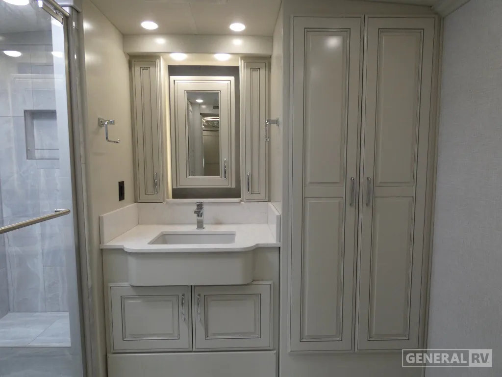 2026 American Coach American Dream 45A — Bathroom vanity with integrated sink, mirrored cabinet, countertop, and tall storage cabinets beside the shower