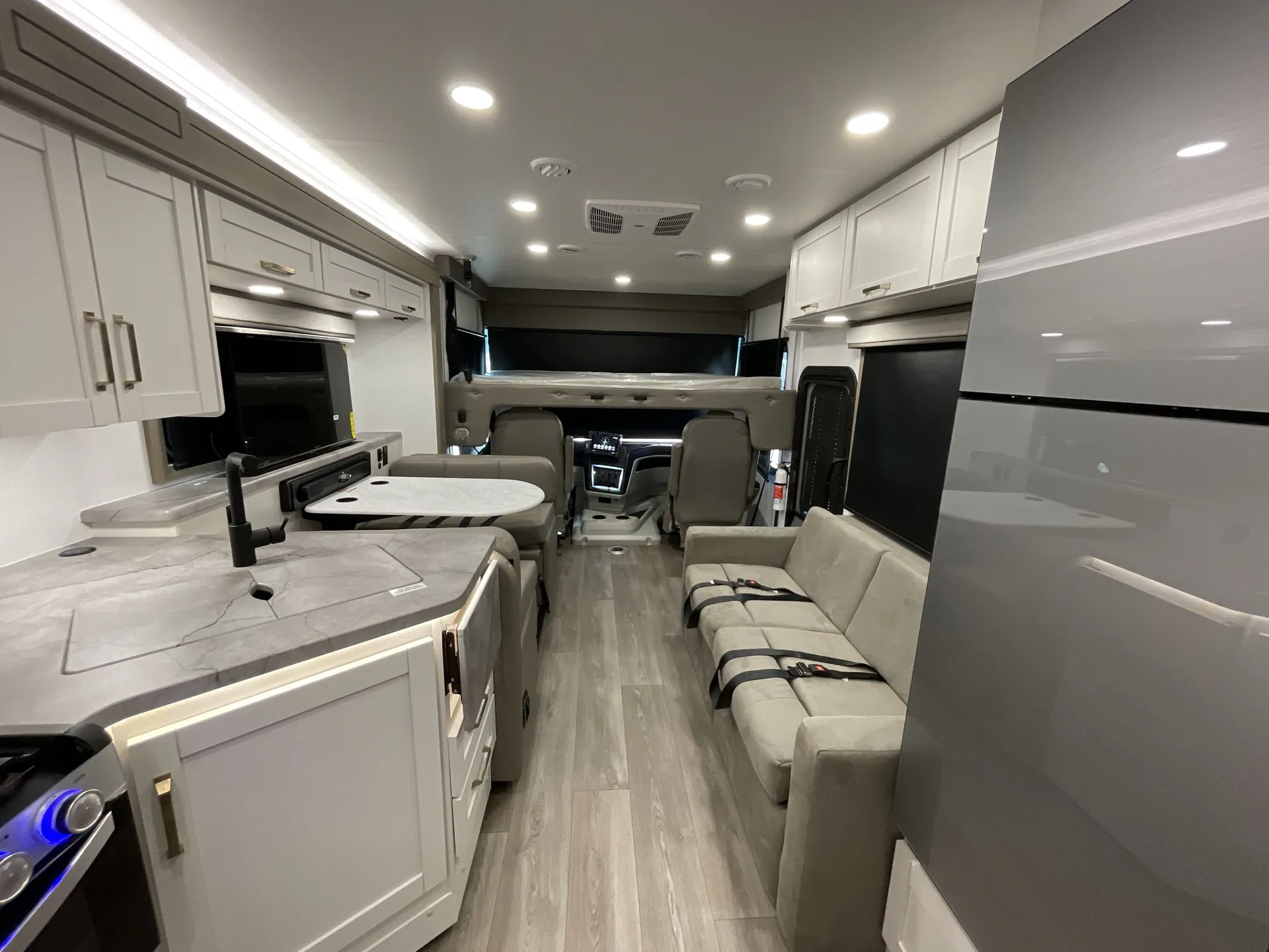 2027 Jayco Alante 29F — Class A motorhome kitchen with sink and counters facing a dinette, sofa, refrigerator, and cockpit