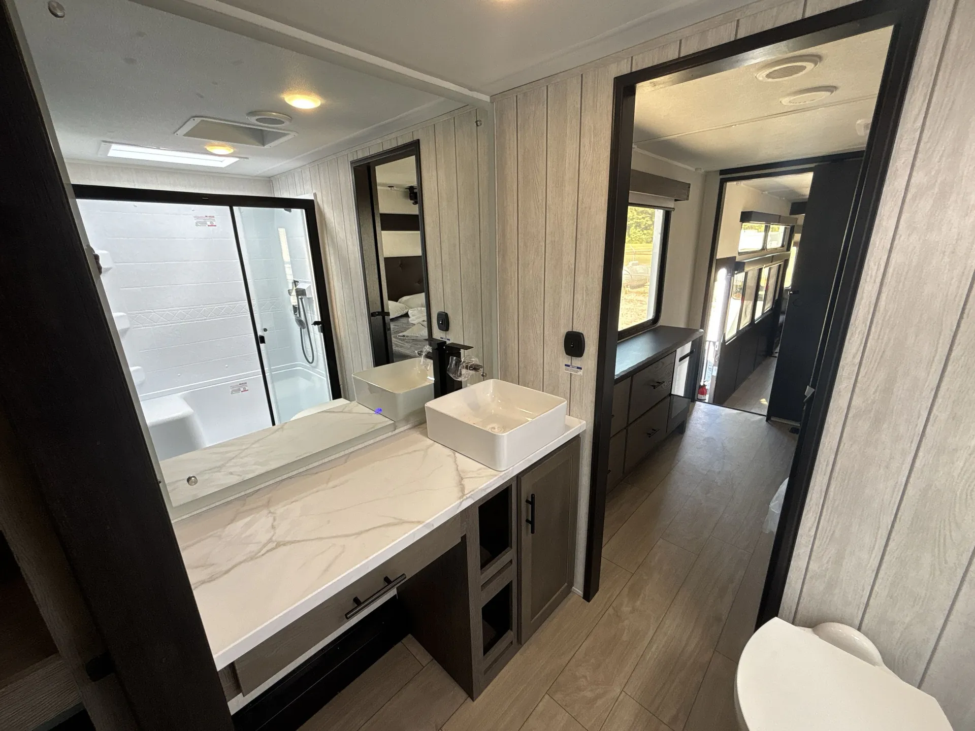 2026 Forest River Arctic Wolf 38LEAH.G — Bathroom vanity with vessel sink and shower, looking through the doorway toward the main bedroom and living area