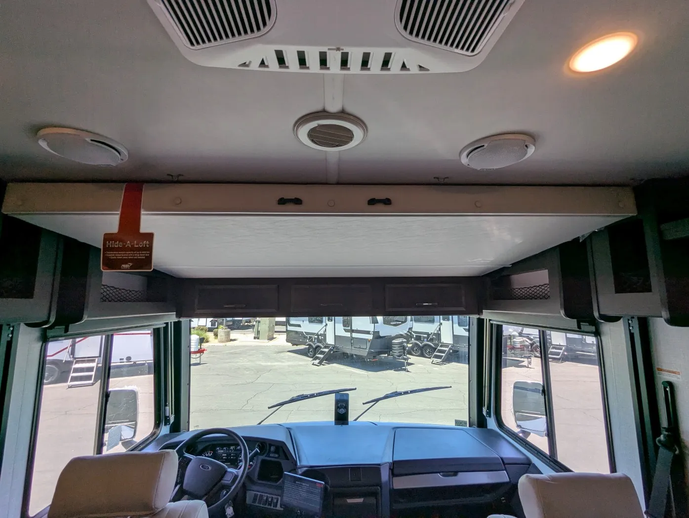 2026 Holiday Rambler Invicta 36Y — Over-cab loft storage and sleeping platform above the visible Class A cockpit dashboard and captain’s chairs