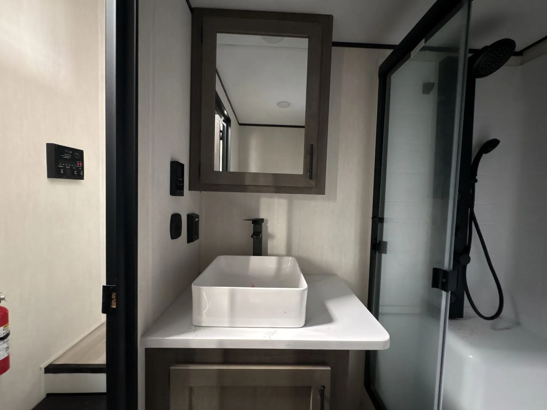 2026 Forest River Cherokee Wolf Pack 397STAY — Bathroom vanity with vessel sink, black faucet, mirrored cabinet, and adjacent glass shower enclosure