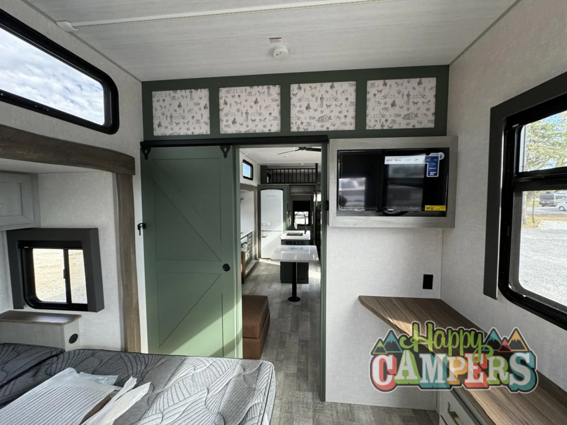 2025 Forest River IBEX RVS3 — Bedroom overview showing the main bed, television console, and open passage toward the trailer living area