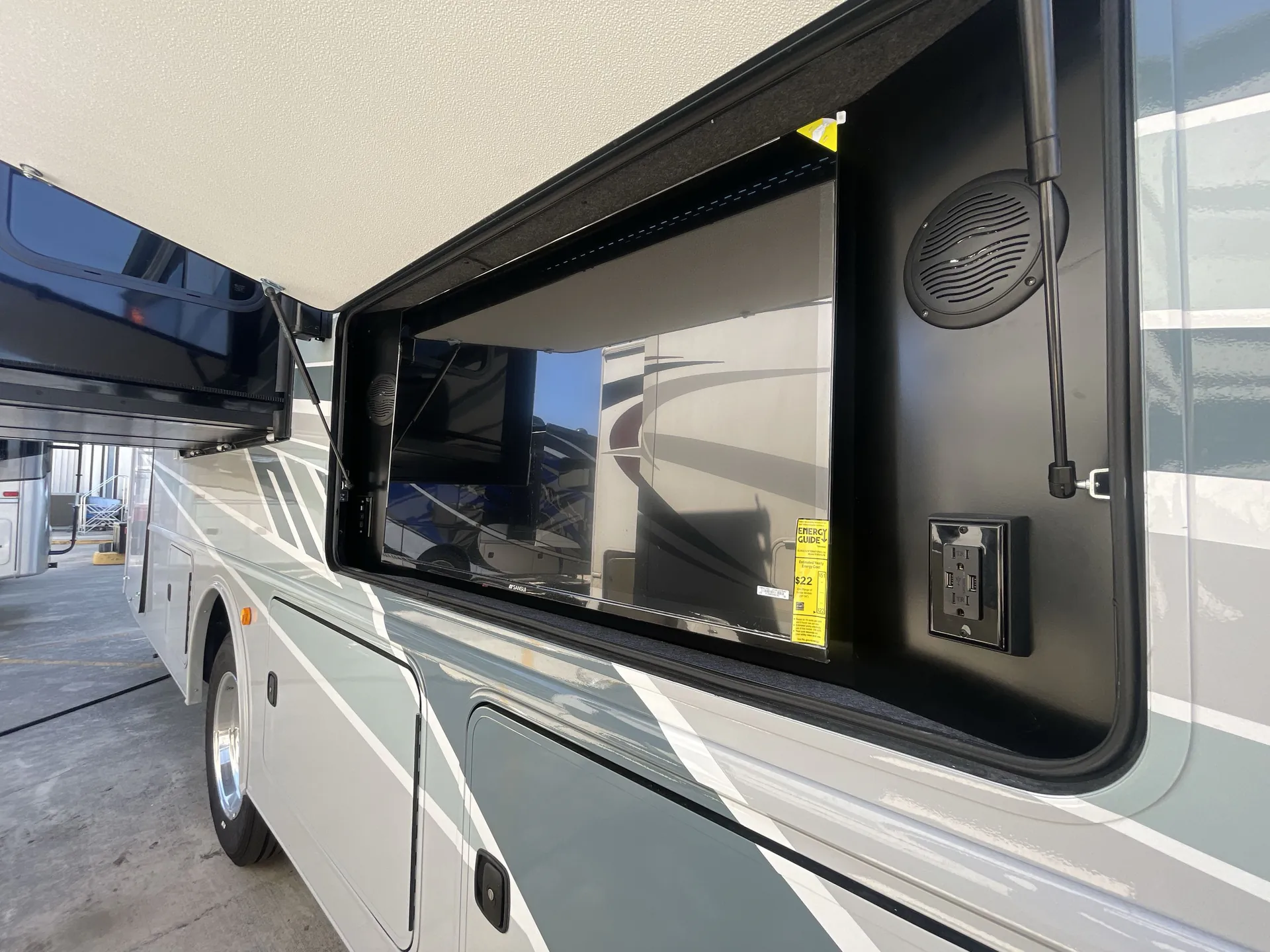 2026 Holiday Rambler Invicta 36Y — The RV exterior side with an extended awning, exterior speakers, outlet, and body panels