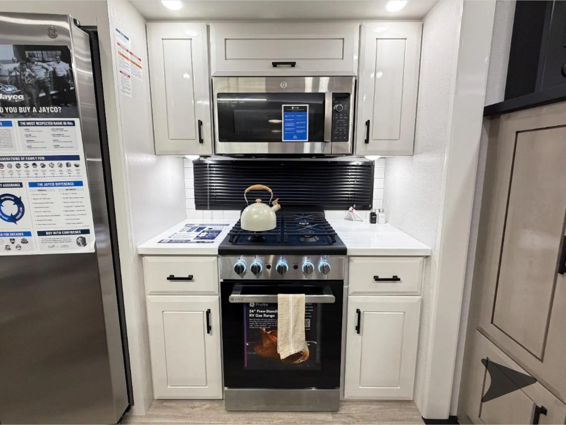 2027 Jayco Pinnacle 39FLOK — Fifth-wheel kitchen galley with refrigerator, microwave, range, oven, countertop, sink area, and white cabinetry