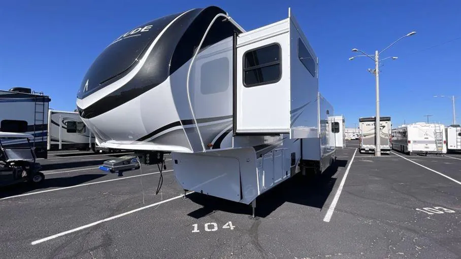 2026 Grand Design Solitude 391DL — Front-side photograph visibly shows the fifth-wheel exterior, front cap, hitch, storage compartments, and slide-out