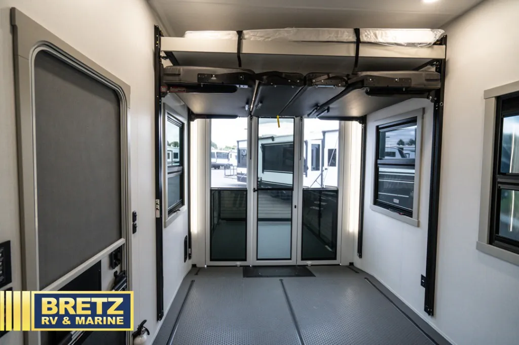 2026 Brinkley Model G 3950 — Fifth wheel garage showing a wide textured cargo floor, rear glass doors, side windows, and overhead fold-away hardware