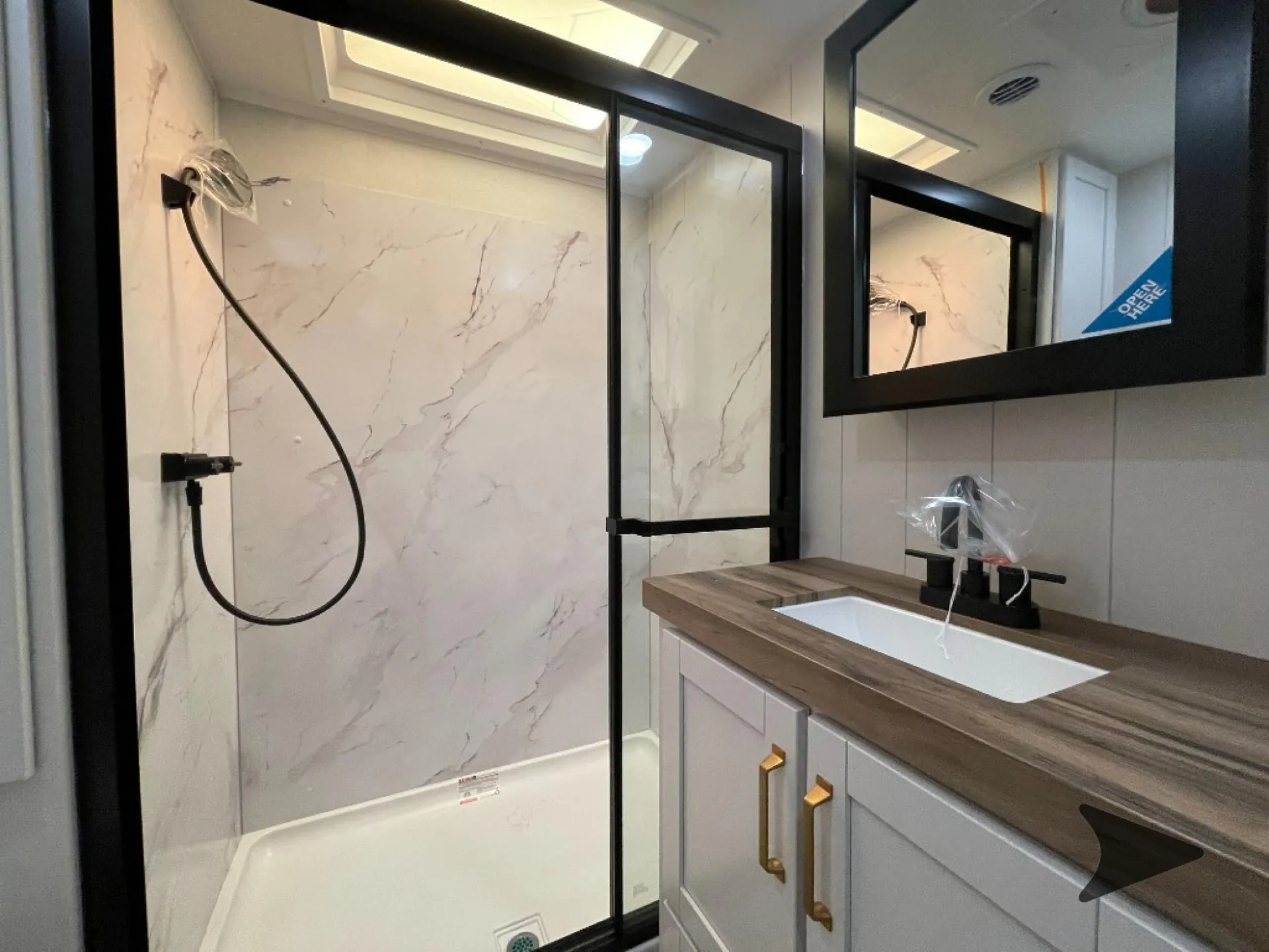2027 Jayco Eagle 355MBQS — Bathroom close view of glass shower, handheld sprayer, skylight, vanity sink, and mirrored cabinet