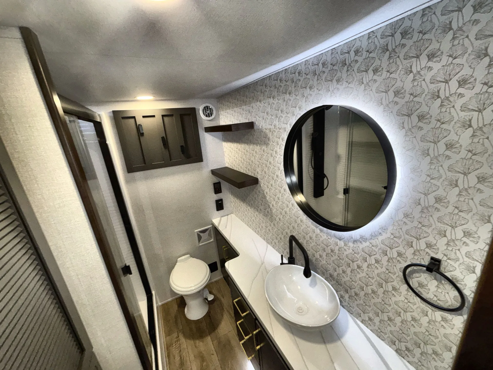 2026 Forest River Cedar Creek Cottage 41FWC — Bathroom with a vessel sink, illuminated round mirror, toilet, vanity drawers, and patterned walls