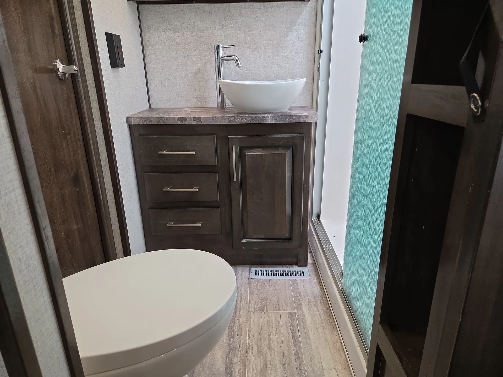 2022 Dutchmen Voltage 4225 — Bathroom vanity with vessel sink, drawers, cabinet, toilet, and adjacent frosted shower door