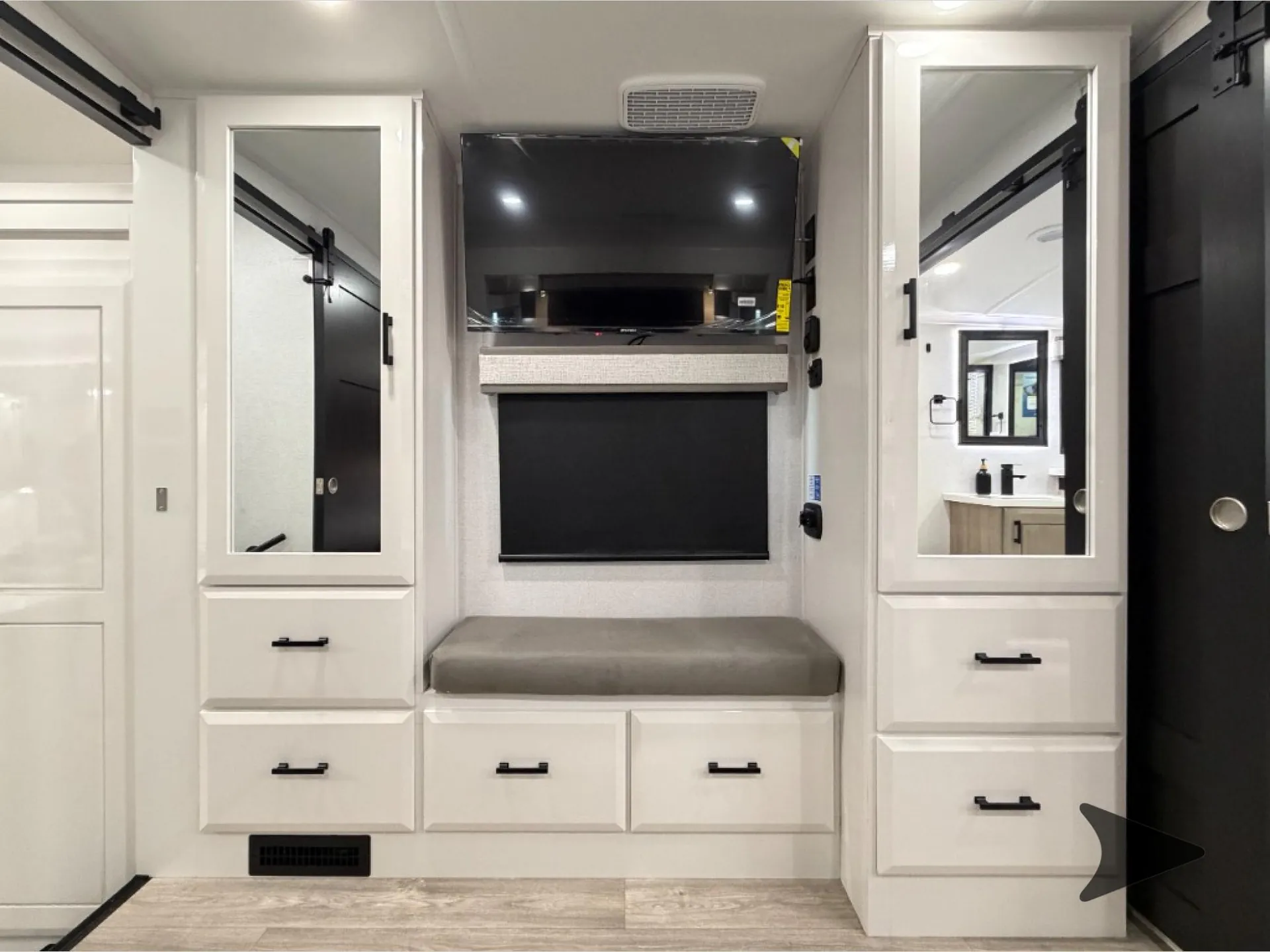 2027 Jayco Pinnacle 39FLOK — Bedroom entertainment wall with television, cushioned bench, drawers, wardrobes, and mirrored cabinet doors