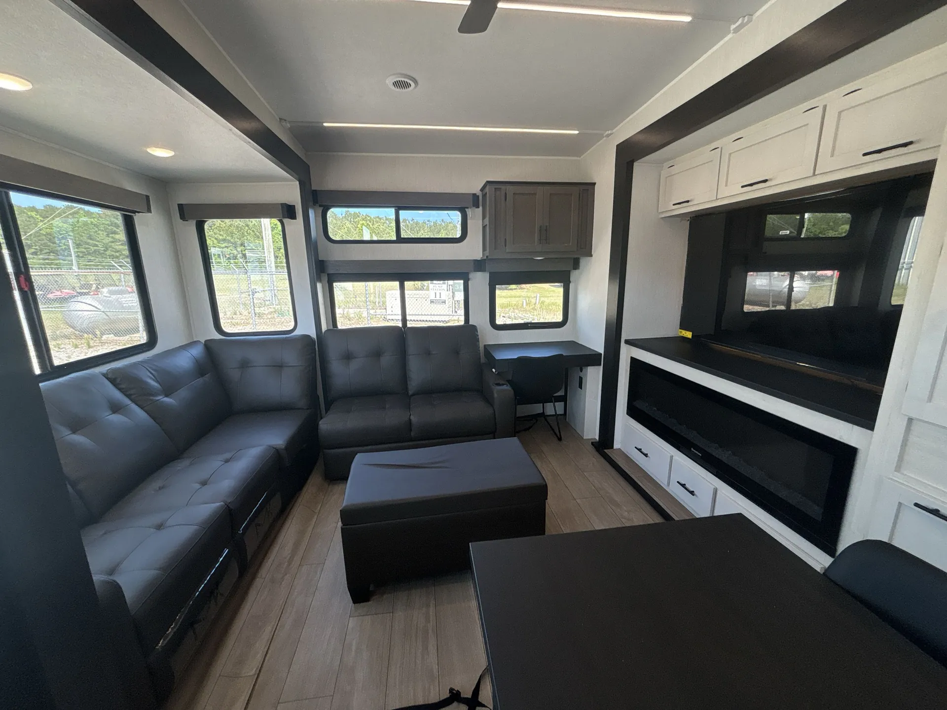 2026 Forest River Arctic Wolf 38LEAH.G — Fifth wheel living room with two sofas, ottoman, entertainment center, and adjacent dining table