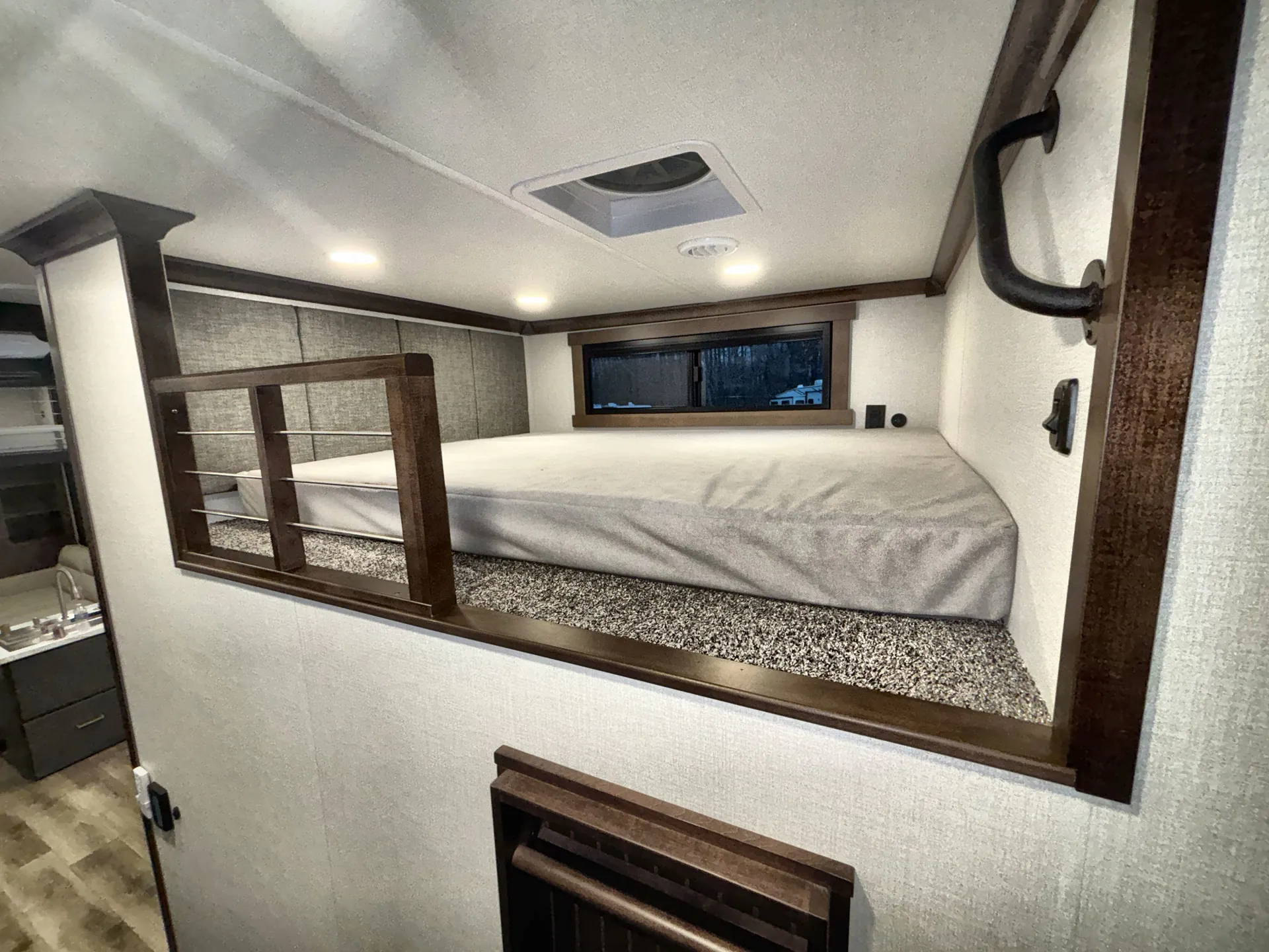 2026 Forest River Cedar Creek Cottage 41FWC — Elevated sleeping loft with mattress and railing above a partially visible kitchen sink and cabinetry