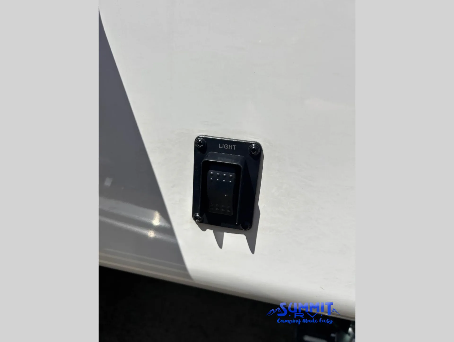 2027 Jayco Eagle 355MBQS — Close-up visibly shows an exterior-installed switch labeled LIGHT on the RV shell