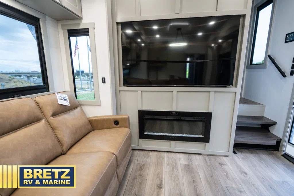 2026 Brinkley Model G 3950 — Living area entertainment wall with large television, electric fireplace, sectional seating, windows, and entry steps