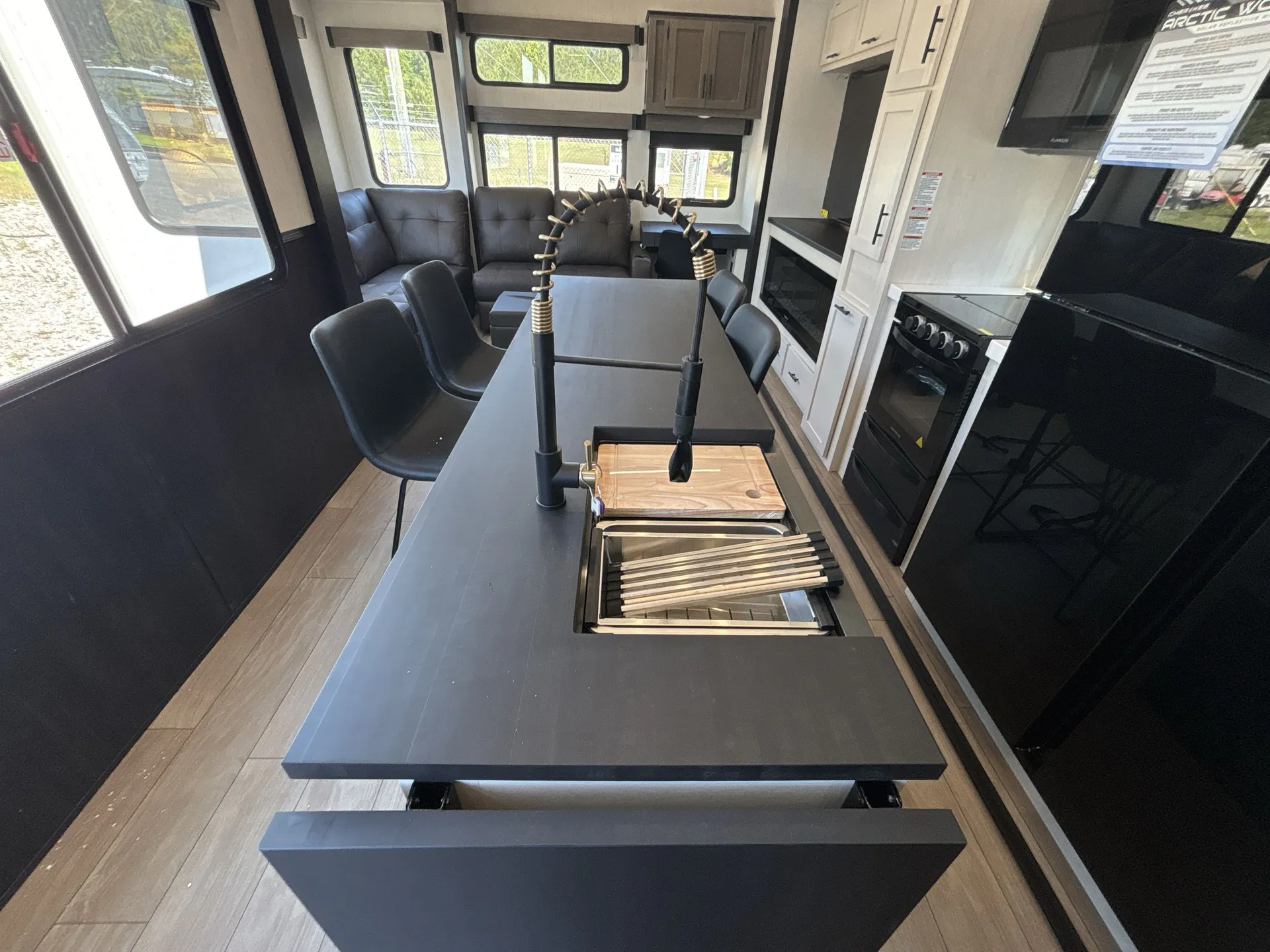 2026 Forest River Arctic Wolf 38LEAH.G — Fifth wheel kitchen island with sink, refrigerator, range, and living seating beyond