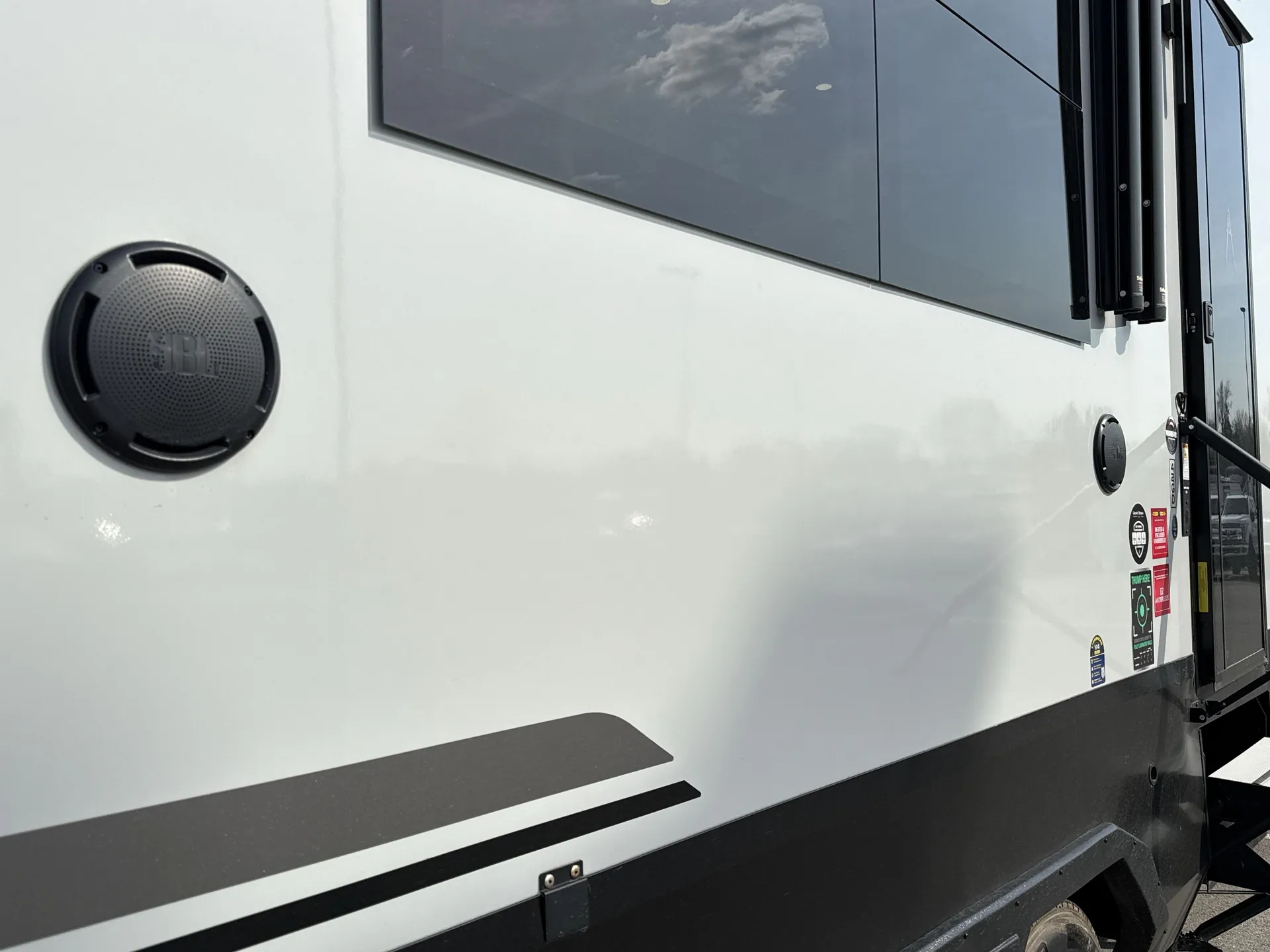 2026 Grand Design Foundation 42GD — Close photograph of the RV exterior side wall, window, speaker, decals, and entry door