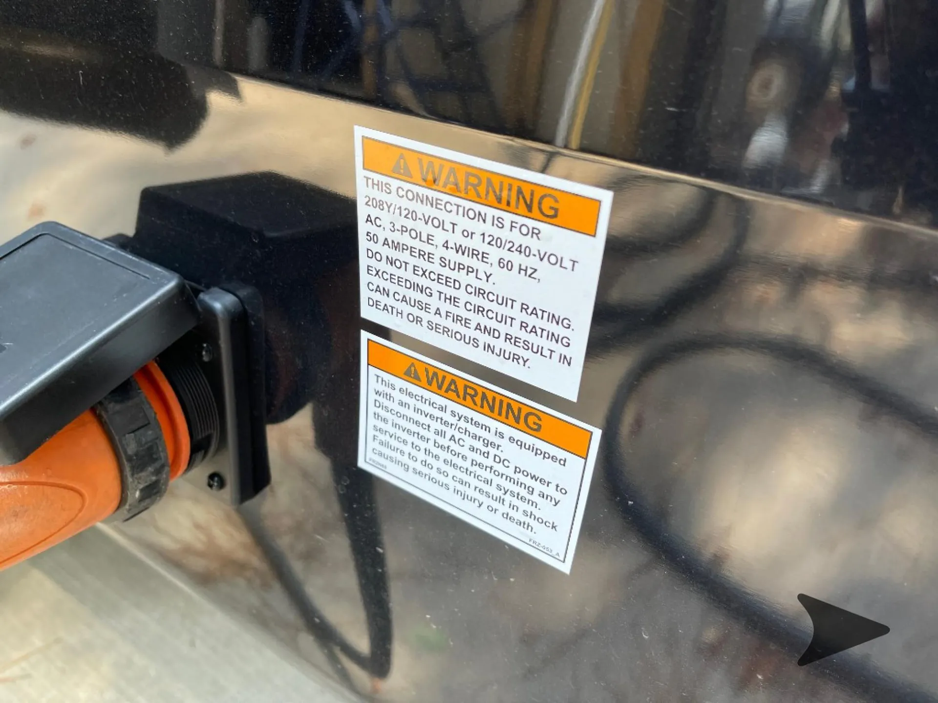 2026 Jayco North Point 377RLBH — Close-up visibly shows the exterior 50-amp electrical inlet and electrical warning labels