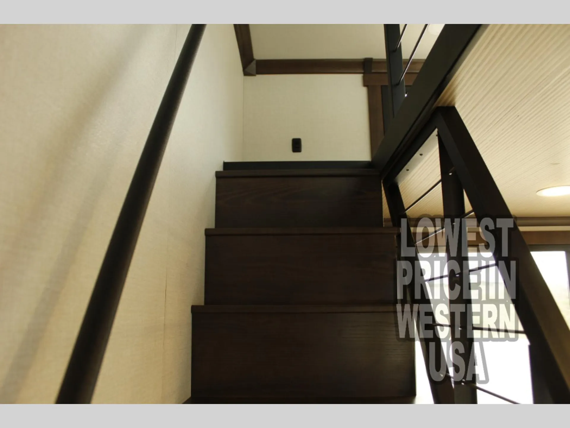 2026 Forest River Cedar Creek Cottage 41FWC — Staircase rises toward an elevated sleeping loft with dark wood steps and black metal railings