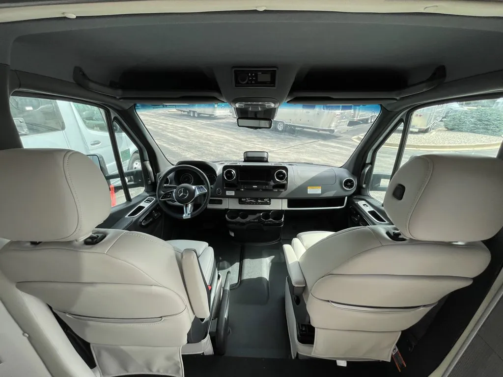 2026 Airstream Atlas Murphy Suite — Class B van cockpit showing steering wheel, dashboard controls, front seats, windshield and side windows