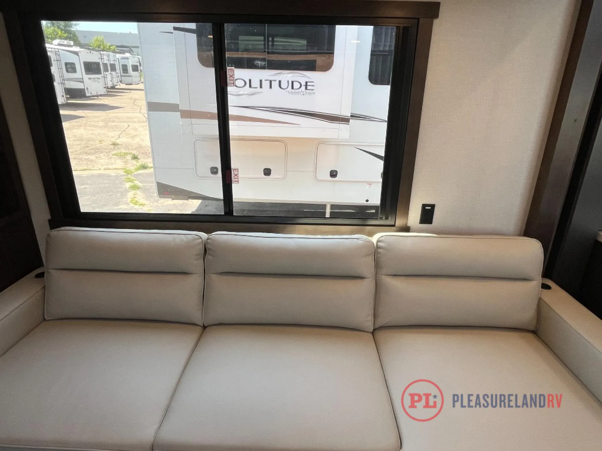 2025 Forest River Cedar Creek Cottage 41FWC — Large upholstered lounge sofa sits beneath a wide window in the fifth wheel living area