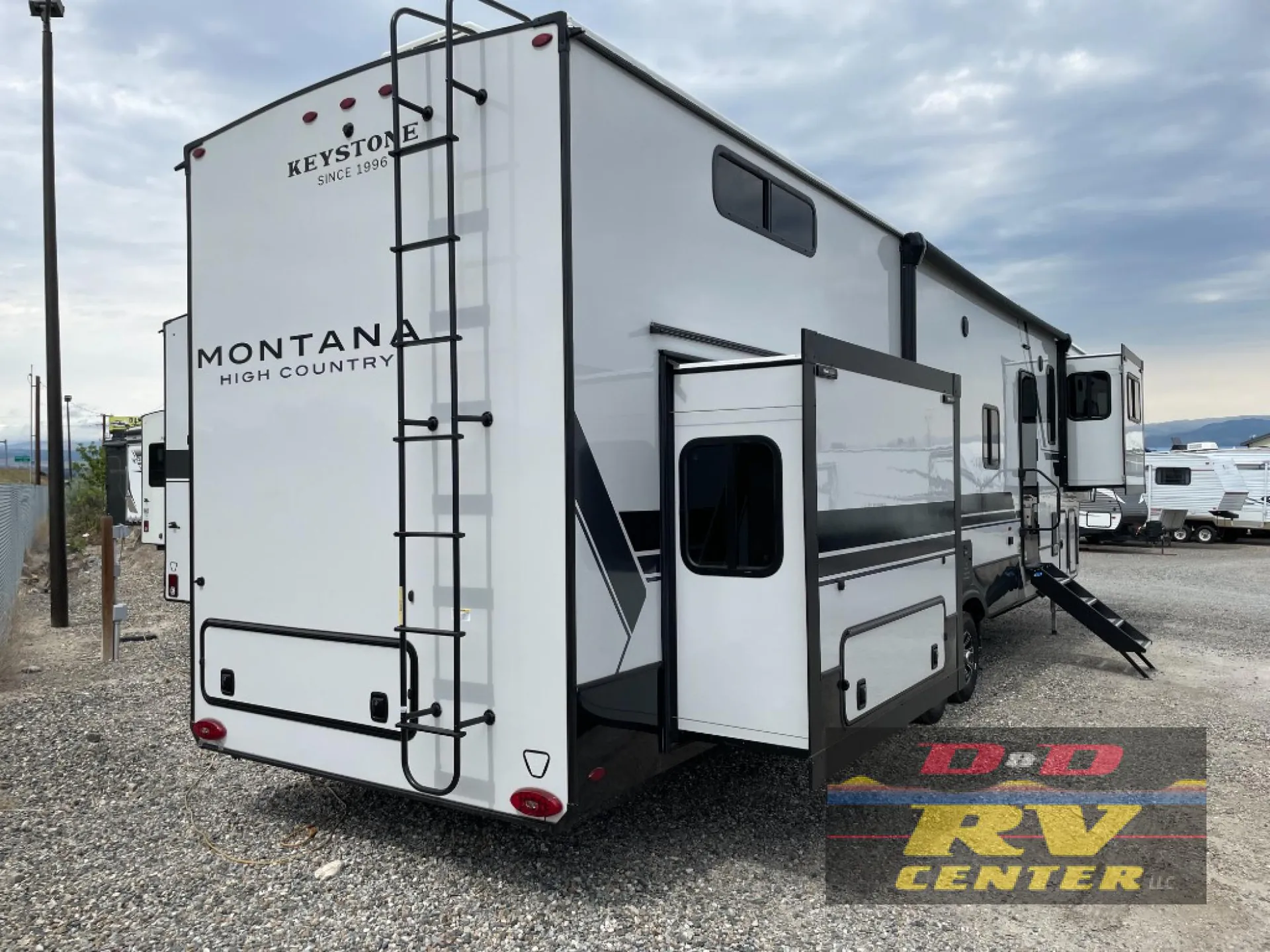 2026 Keystone Montana High Country 377FL — The rear and side exterior shell of the Montana fifth-wheel RV, including ladder, slide-out, and storage doors