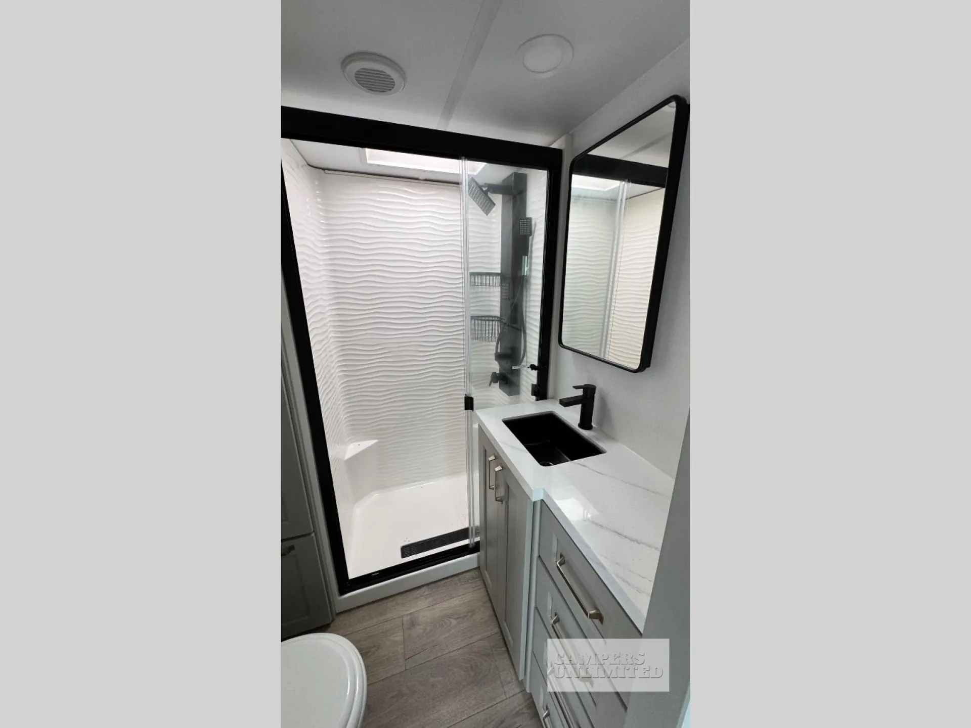 2026 Brinkley Model G 3950 — Bathroom with glass-enclosed shower, wave-textured wall, black sink, vanity countertop, and mirror