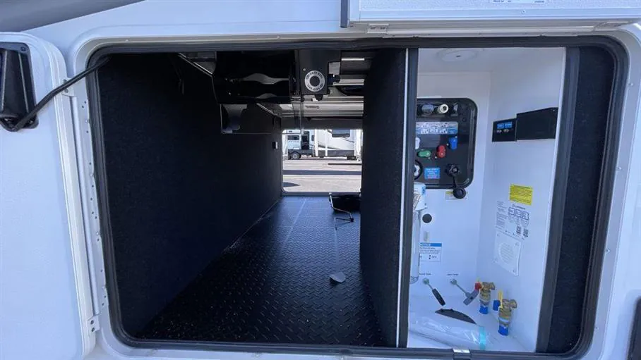 2026 Grand Design Solitude 391DL — Open exterior compartment visibly shows a large pass-through storage bay and installed utility controls