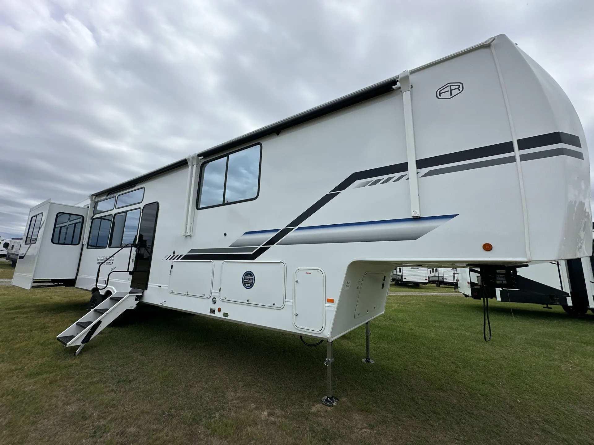 2026 Forest River Arctic Wolf 38LEAH.G — The RV's exterior side, front cap, awning hardware, entry steps, and landing gear