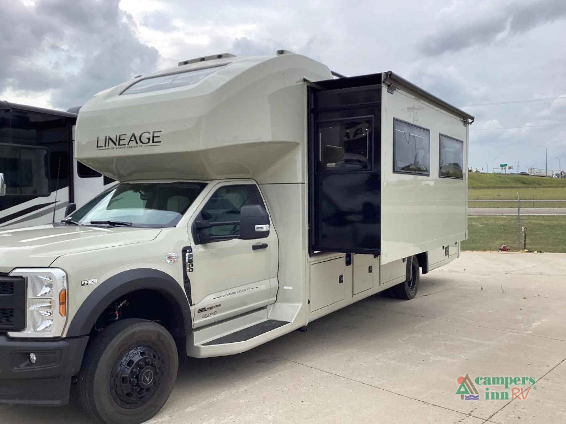 2027 Grand Design Lineage Series F 31ZW — The motorhome exterior with a large extended slide-out, cab, wheel, and exterior storage compartments