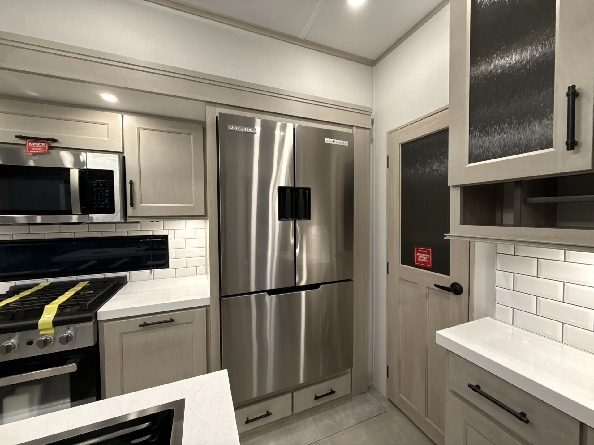 2026 Grand Design Solitude 391DL — Fifth wheel kitchen appliance wall with refrigerator, range, microwave, cabinetry, and countertop