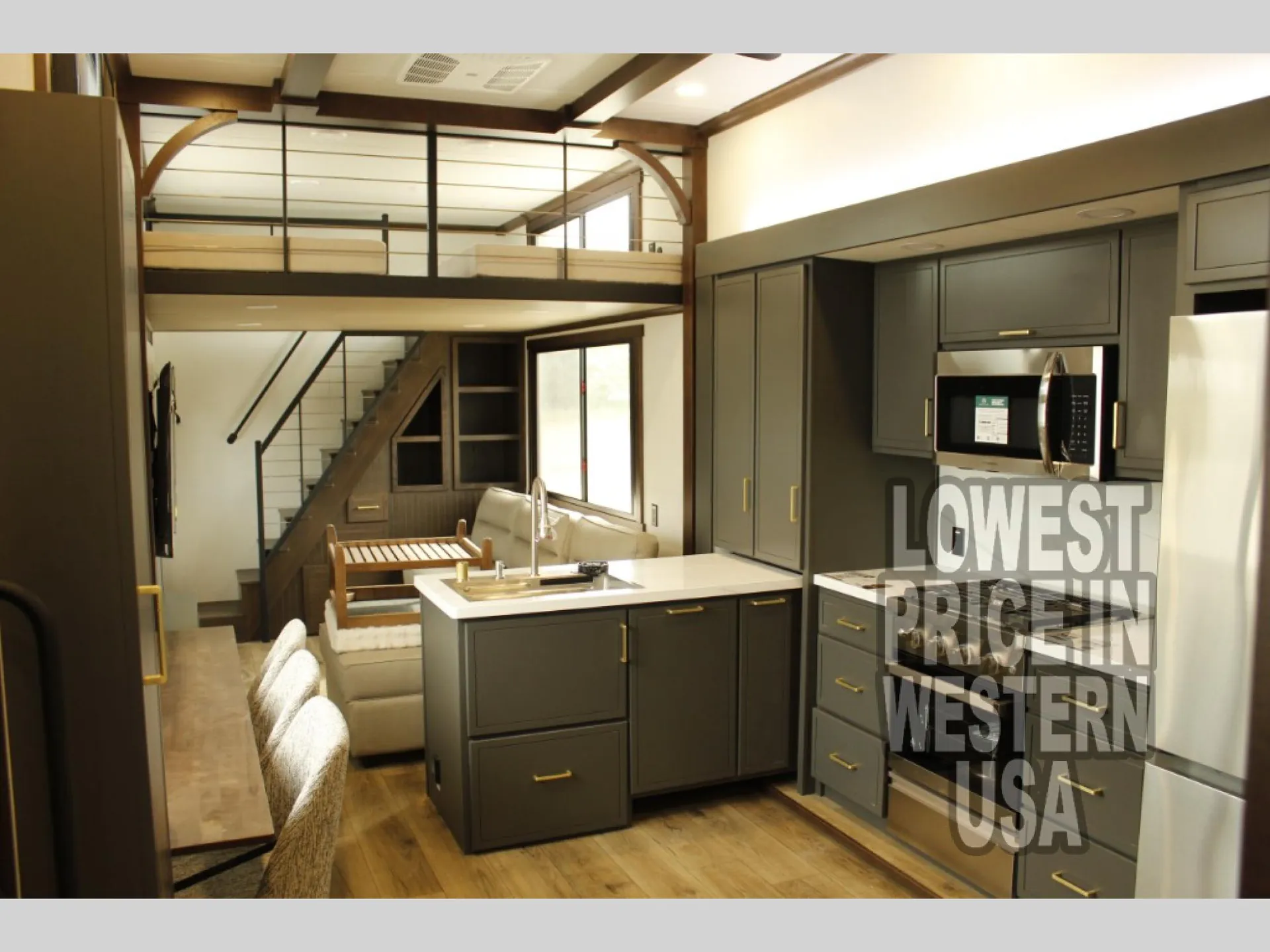 2026 Forest River Cedar Creek Cottage 41FWC — Kitchen island, cabinetry, refrigerator, lounge seating, and an elevated sleeping loft with staircase are visible together
